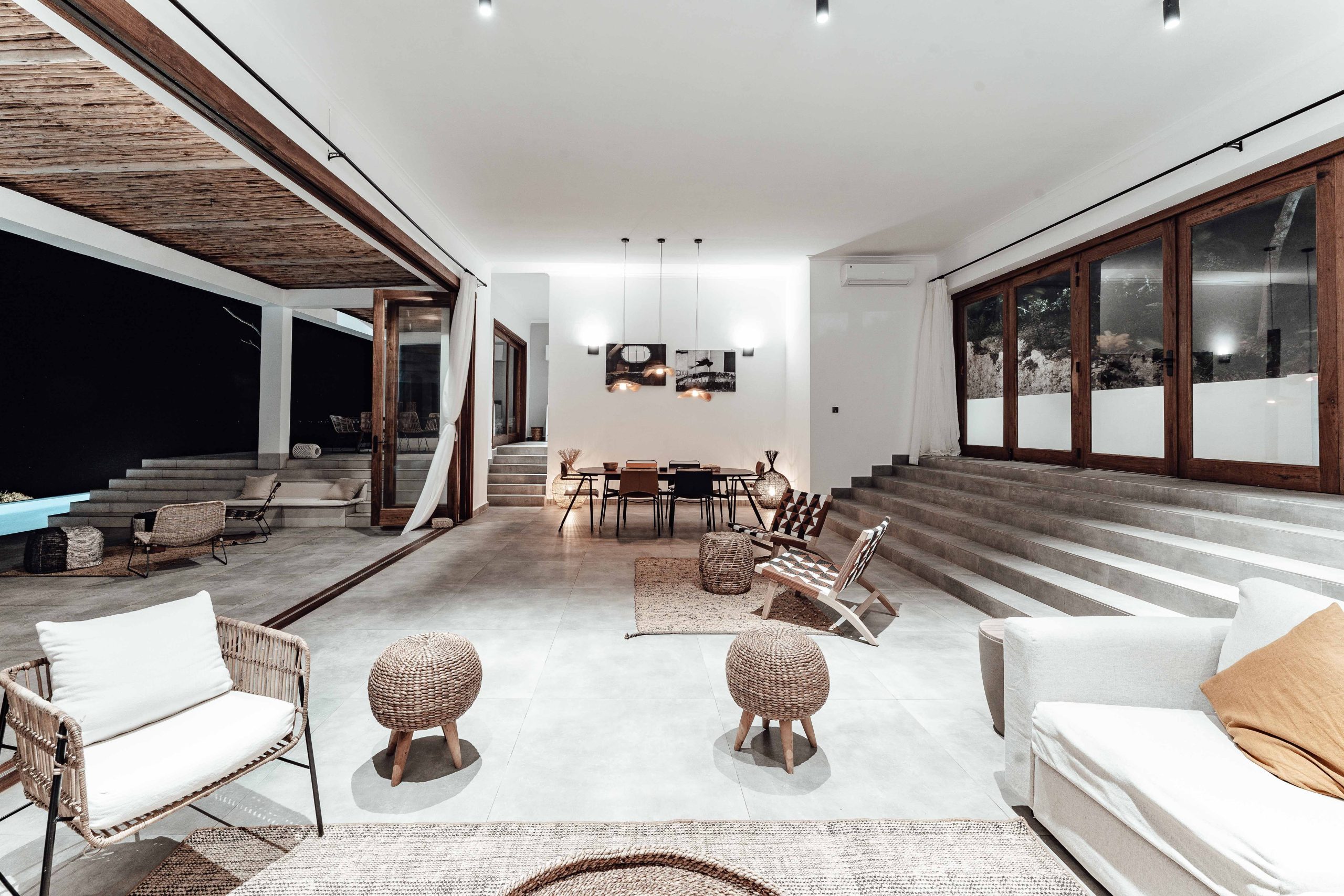 Stylish and spacious modern living area with pool view, featuring neutral decor and open design.
